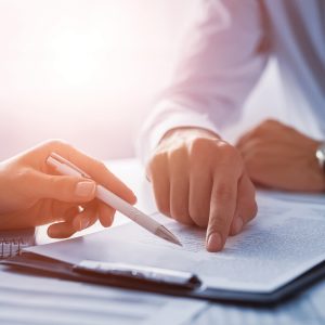 Business people negotiating a contract. Human hands working with documents at desk and signing contract.